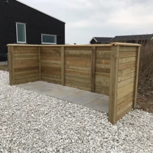Træaffaldsskjul ved moderne hus på grusgrund