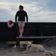 Person står ved strand med hund